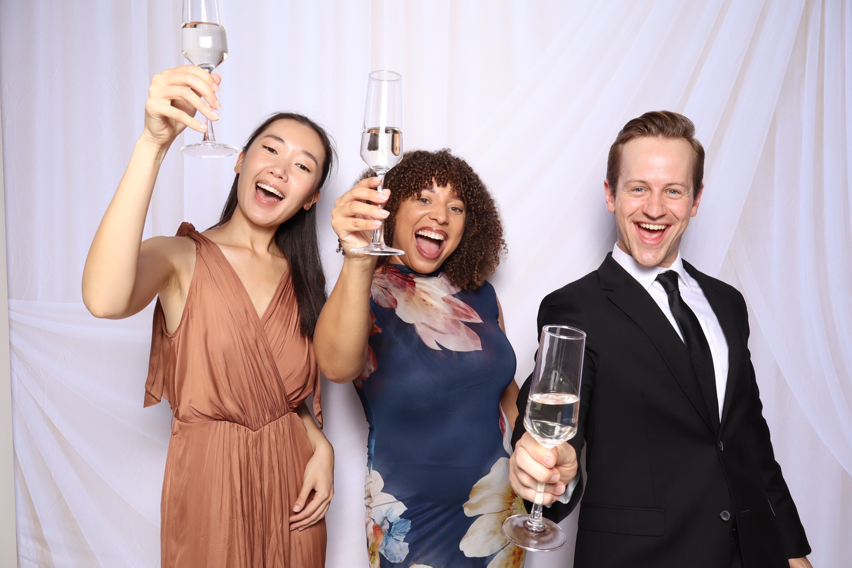 Three guests celebrating with champagne glasses at the Studio Flor photo booth.